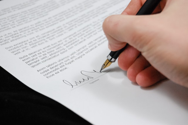 Hand signing a document with a black fountain pen