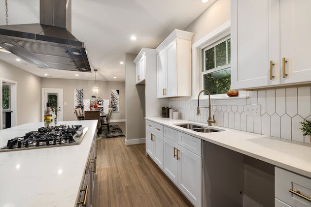 a white kitchen with gold hardware on the cabinets