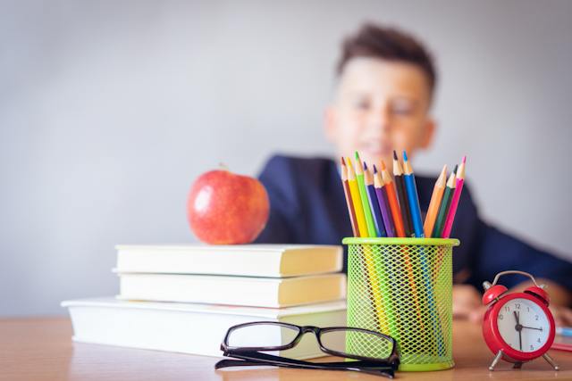 child sitting behind a desk full of school supplies